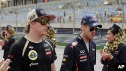 Red Bull driver Sebastian Vettel of Germany, second right, and Lotus driver Kimi Raikkonen of Finland, second left, arrive at the drivers track parade ahead of the Formula One Grand Prix at the Bahrain International Circuit in Sakhir, Bahrain, Sunday, Apr