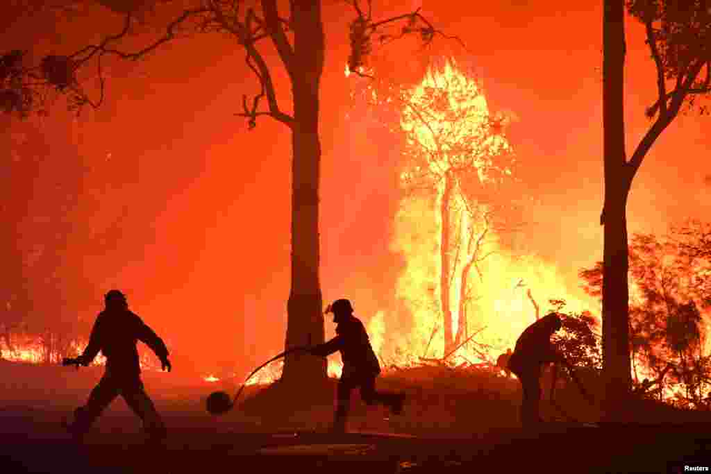 Rural Fire Service (RFS) volunteers and NSW Fire and Rescue officers fight a bushfire encroaching on properties near Termeil, Australia, Dec. 3, 2019.