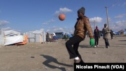 Un migrant joue avec un ballon dans la "Jungle" de Calais, France (Nicolas Pinault/VOA)