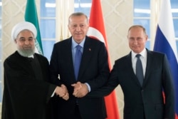 FILE - From left: Iranian President Hassan Rouhani, Turkish President Recep Tayyip Erdogan and Russian President Vladimir Putin shake hands during their meeting in Ankara, Turkey, Sept. 16, 2019.