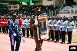 A member of The Namibian Defence Forces carries a portrait of the late Namibian President Hage Geingob, at Independence Stadium in Windhoek, Namibia, February 24, 2024 during his memorial service.