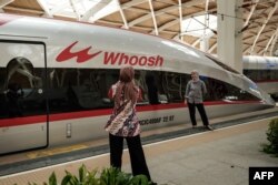 Sejumlah pengunjung berfoto di depan kereta cepat Jakarta-Bandung yang dinamakan Whoosh dalam acara peresmian di stasiun Halim, Jakarta, 2 Oktober 2023. (Foto: Yasuyoshi Chiba/AFP)