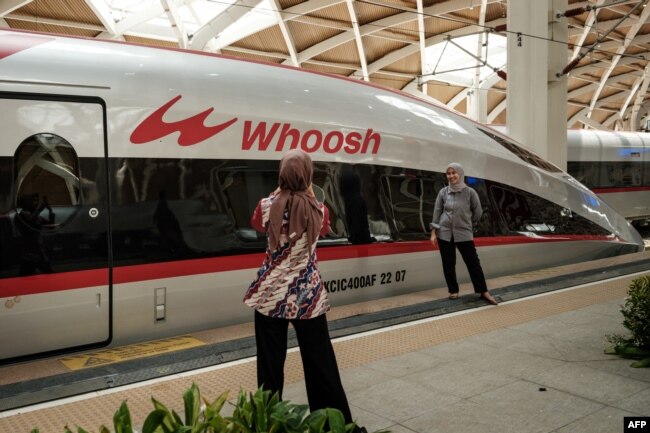 Sejumlah pengunjung berfoto di depan kereta cepat Jakarta-Bandung yang dinamakan Whoosh dalam acara peresmian di stasiun Halim, Jakarta, 2 Oktober 2023. (Foto: Yasuyoshi Chiba/AFP)