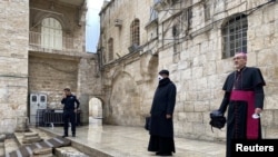 Archbishop Pierbattista Pizzaballa, apostolic administrator of the Latin Patriarchate of Jerusalem stands at the entrance to the Church of the Holy Sepulchre in Jerusalem for the Good Friday service April 10, 2020.