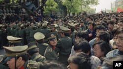 FILE - Students demonstrators scuffle with police as they try to break the guard line to march to the Tiananmen Square in Beijing, April 27, 1989. 