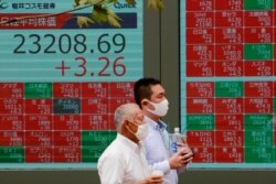 People walk by an electronic stock board of a securities firm in Tokyo, Monday, Sept. 7, 2020. Asian stock markets were mixed Monday after Wall Street turned in its biggest weekly decline in more than two months.