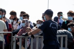 Migrants wait to enter a new temporary refugee camp in Kara Tepe, near the capital of the northeastern island of Lesbos, Greece, Sept. 17, 2020.