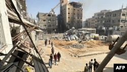 Palestinians walk past damaged and destroyed buildings in Beit Lahia the northern Gaza Strip, Oct. 26, 2024. 