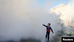 A Palestinian boy plays as disinfectants are sprayed by workers to sanitize cars and shops amid the coronavirus disease (COVID-19) outbreak in Hebron in the Israeli-occupied West Bank.