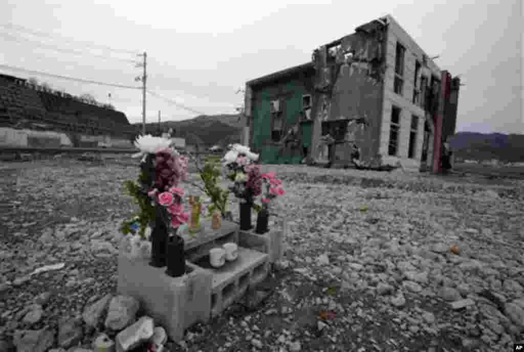 Flowers and water are offered on a makeshift altar in a vacant land next to a damaged building in a neighborhood destroyed by the March 11 earthquake and tsunami in Onagawa, Miyagi Prefecture, Friday, March 9, 2012, two days before the one-year anniversar