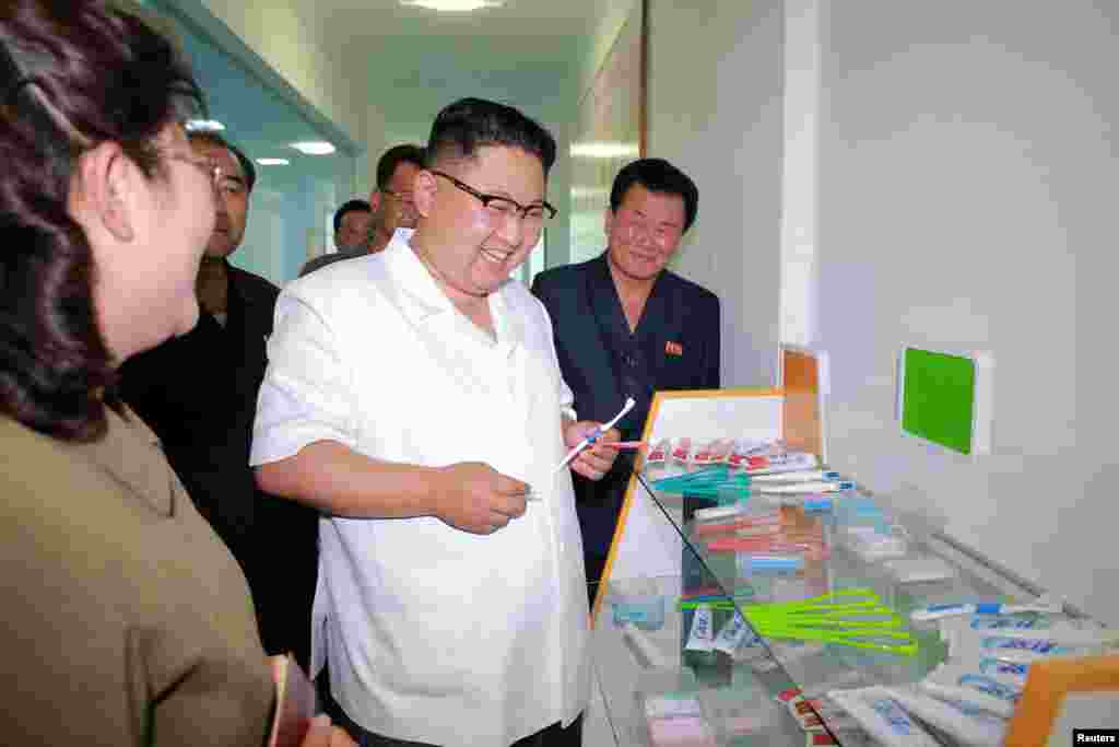김정은 국무위원장이 새 치과용품 공장에서 생산한 제품을 들고 만족해하고 있다.