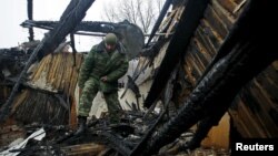 FILE - A Russian member of the Joint Center on Control and Coordination of issues related to the cease-fire regime and the stabilization of the situation walks amid the debris of a house damaged by shelling in Donetsk, Ukraine, Nov. 29, 2015.