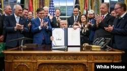 特朗普总统星期三(2025年11月12日)在白宫椭圆形办公室向媒体展示他签署生效的恢复联邦政府运作的拨款法案。(白宫官方照片)