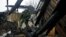 FILE - A Russian member of the Joint Center on Control and Coordination of issues related to the cease-fire regime and the stabilization of the situation walks amid the debris of a house damaged by shelling in Donetsk, Ukraine, Nov. 29, 2015.