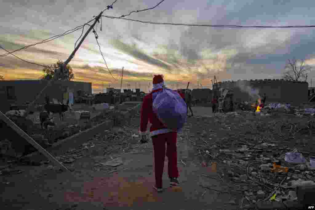 A man dressed as Santa Claus arrives to distribute toys to children living in an impoverished neighborhood in Iraq&#39;s southern city of Basra, Dec. 26, 2020.