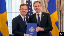 Menlu AS Antony Blinken, kanan, berfoto bersama PM Swedia Ulf Kristersson memegang dokumen Aksesi Swedia ke dalam NATO di kantor Departemen Luar Negeri AS, Kamis, 7 Maret 2024, di Washington, DC. (Foto: AP/Jess Rapfogel)