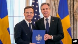 El secretario de Estado, Antony Blinken, a la derecha, posa para una fotografía con el primer ministro sueco, Ulf Kristersson, sosteniendo los instrumentos de adhesión de Suecia a la OTAN en la sala Benjamin Franklin del Depto. de Estado, el 7 de marzo de 2024, en Washington.