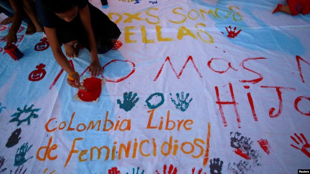 FILE - Girls paint a banner during a demonstration to protest the violence against and killings of women, in Cartagena, Colombia, Oct. 27, 2016. The words at bottom left read: "Colombia Femicide Free."