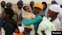 FILE - Zimbabwean women react as they wait to casts their votes at a polling station in Domboshava, about 45 km (28 miles) north of Harare, July 31, 2013.