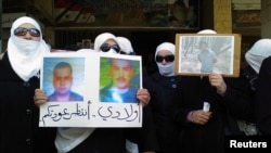 FILE - Women hold pictures of missing relatives as they protest against Syria's President Bashar al-Assad, in Daria, near Damascus, Jan. 19, 2012. 