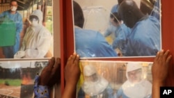 Delegates paste enlarged photos of health workers at work in affected west African countries prior to attending an Ebola preparedness conference in Johannesburg, Oct. 10, 2014.