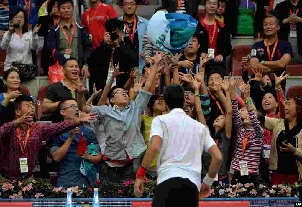 Serbia's Novak Djokovic throws a towel into the crowd after winning the men's singles match against Lukas Rosol of the Czech Republic at the China Open tennis tournament in Beijing, China. Djokovic won 6-0, 6-3.
