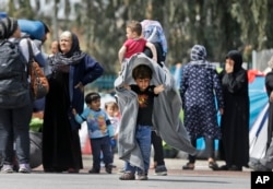 Migrants carrying their belongings walk in the Athens port of Piraeus, April 7, 2016.