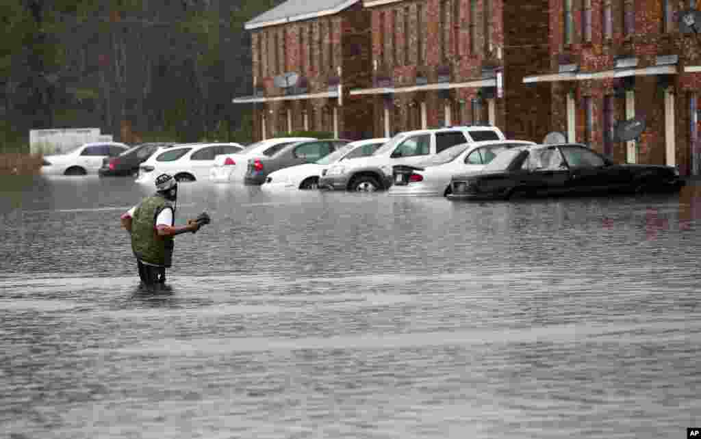 Một người đàn ông lội qua nước lũ ở Hammond, bang Louisiana. Mưa lớn hành hoành ở phía Bắc Louisiana bước sang ngày thứ tư, làm vài trăm người kẹt trong nhà của họ, làm nhiều đường không thể đi qua và gây ngập lụt trên diện rộng.