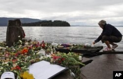 FILE - A woman lights a candle in Sundvollen, facing Utoya island, where gunman Anders Behring Breivik killed at least 68 people, near Oslo, Norway, July 26, 2011. Breivik told a court Wednesday he is the victim of inhuman prison conditions.