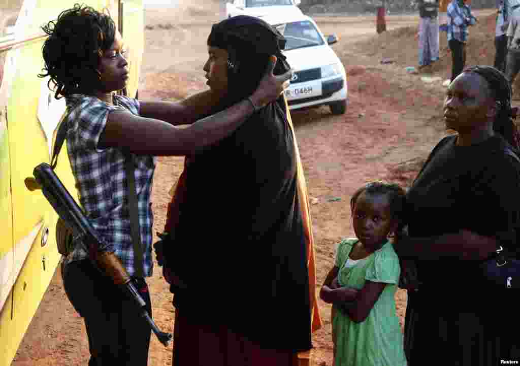 A police officer in regular clothing searches female passengers travelling to Nairobi for weapons, in the town of Mandera at Kenya-Somalia border.