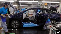 In this Oct. 30, 2017, photo, workers of a Toyota Motor Corp. assemble a Mirai fuel cell vehicle at the automaker's Motomachi plant in Toyota, western Japan. (AP Photo/Yuri Kageyama)