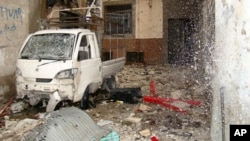 Water spurts out of a broken pipe at a damaged building, next to a damaged vehicle, in the old city of Homs March 30, 2012.