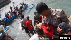 A police officer carries an unconscious child who was on the boat that capsized after hitting a reef off the coast of Sukapura, at Jayanti beach in Indonesia's West Java province on July 24, 2013.