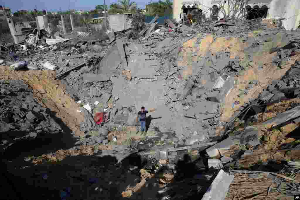 A Palestinian youth stands in the crater of a destroyed house following overnight Israeli missile strikes, in Al-Qarara, east of Khan Younis, southern Gaza Strip.