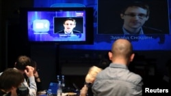 Journalists listen to a speech and a question posed by former U.S. spy agency NSA contractor Edward Snowden, at a media center during Russian President Vladimir Putin's live broadcast nationwide phone-in, in Moscow, Russia, April 17, 2014.