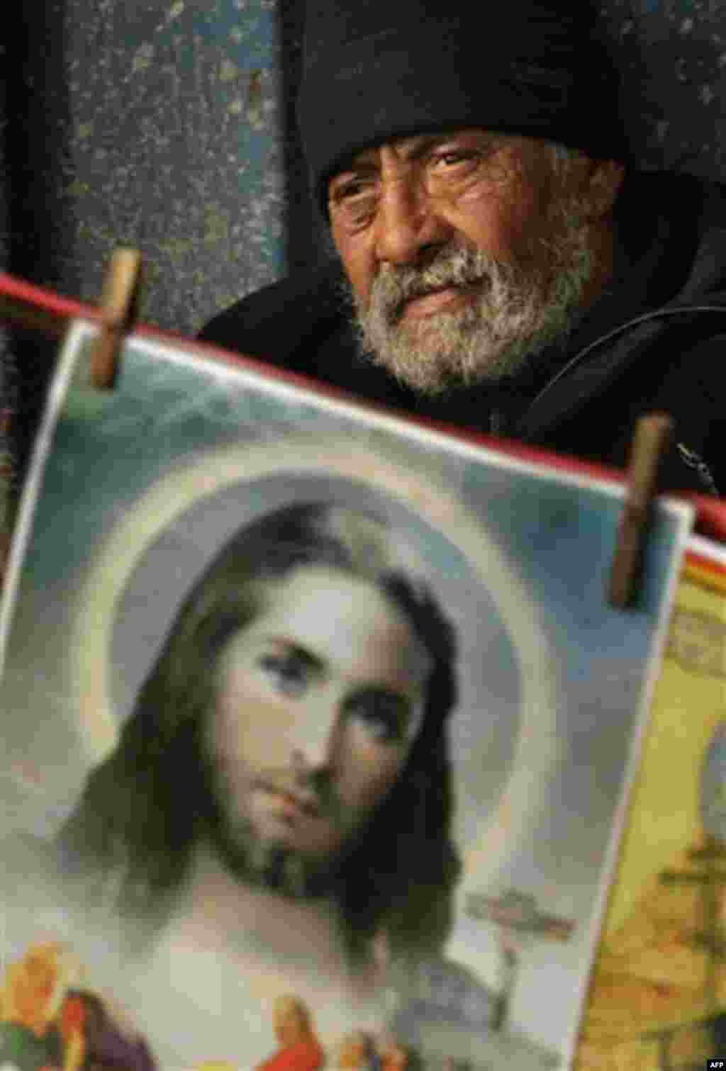 An elderly Romanian man is seen behind a religious picture outside the Saint Mina or Menas church in Bucharest, Romania, Thursday, Nov. 11, 2010. Thousands wait long hours to touch the remains of the saint who, according to Romanian popular belief, offers