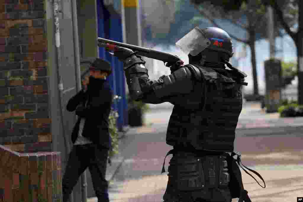 Un policía apunta una escopeta durante una protesta estudiantil en Bogotá, el sábado 23 de noviembre de 2019. Las autoridades colombianas mantienen una acentuada presencia policial y militar en la capital del país tras dos días de disturbios. (Foto AP/Ivan Valencia)