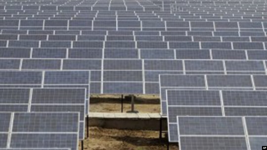 An Indian security guard walks among solar panels at the newly inaugurated solar photovoltaic power plant at Khadoda, in Sabarkantha district, about 90 kilometers (56 miles) from Ahmadabad, India, Friday, June 10, 2011