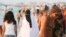 A woman wearing a bikini walks past a woman wearing a niqab on a beach in the Mediterranean city of Alexandria, about 220 km northwest of Cairo,Egypt, Aug. 7, 2009. 