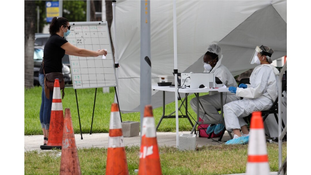 FILE - Health care workers take information from people in line at a walk-up COVID-19 testing site during the coronavirus pandemic, in Miami Beach, Florida, July 17, 2020.