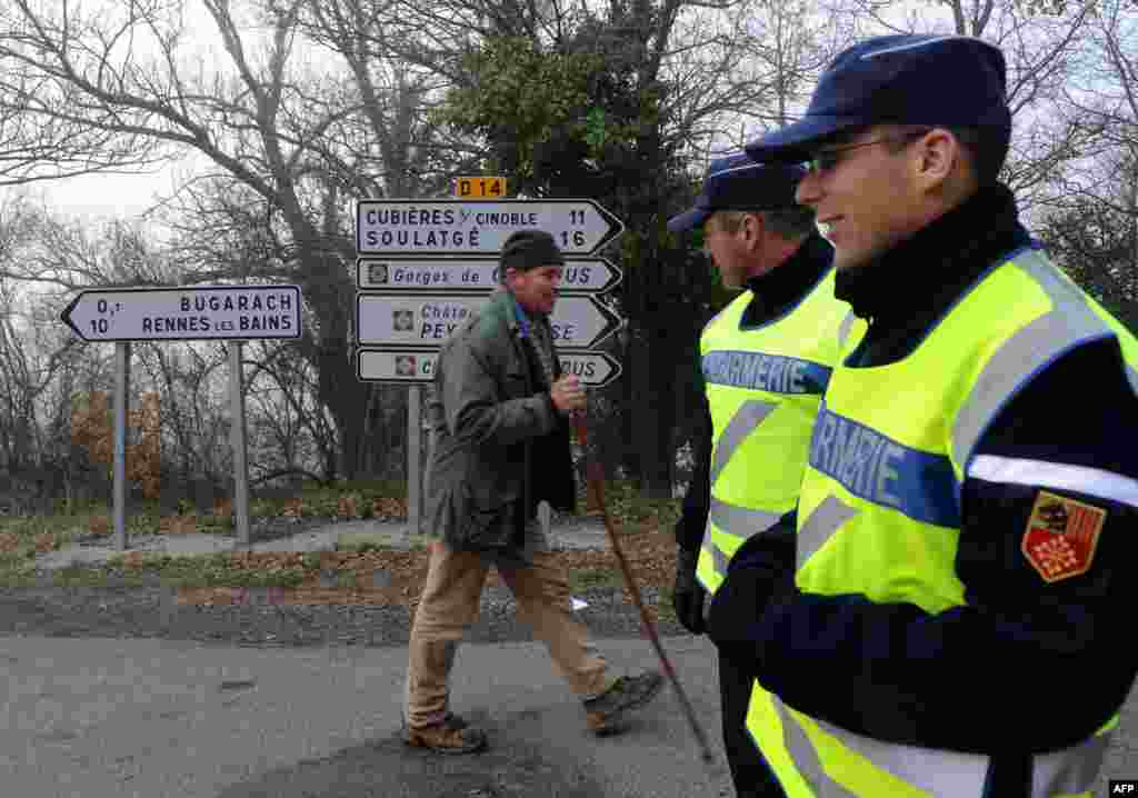 A man walks with a stick past gendarmes controlling access to the French southwestern village of Bugarach, Dec. 20, 2012. 