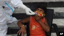 အိန္ဒိယနိုင်ငံ New Delhi မြို့က ကလေးငယ်တဦးကို COVID ရောဂါ ရှိ၊ မရှိ စစ်ဆေးပေးနေတဲ့ မြင်ကွင်း။ (သြဂုတ် ၀၇၊ ၂၀၂၀)