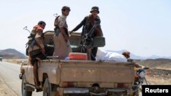 FILE - Fighters loyal to Yemen's Saudi-backed government ride a pickup truck on their way to a position near the frontline facing Iran-backed Huthi rebels in the country's northeastern province of Marib, on Oct. 17, 2021.