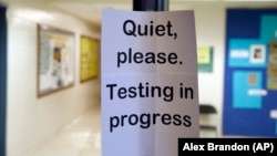 This file photo shows a sign posted while a test is being given to high school students. Many colleges switched to test-optional admissions during the pandemic. (AP Photo/Alex Brandon)