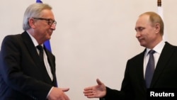 Russian President Vladimir Putin, right, approaches to shake hands with European Commission President Jean-Claude Juncker during a meeting in St. Petersburg, Russia, June 16, 2016. 