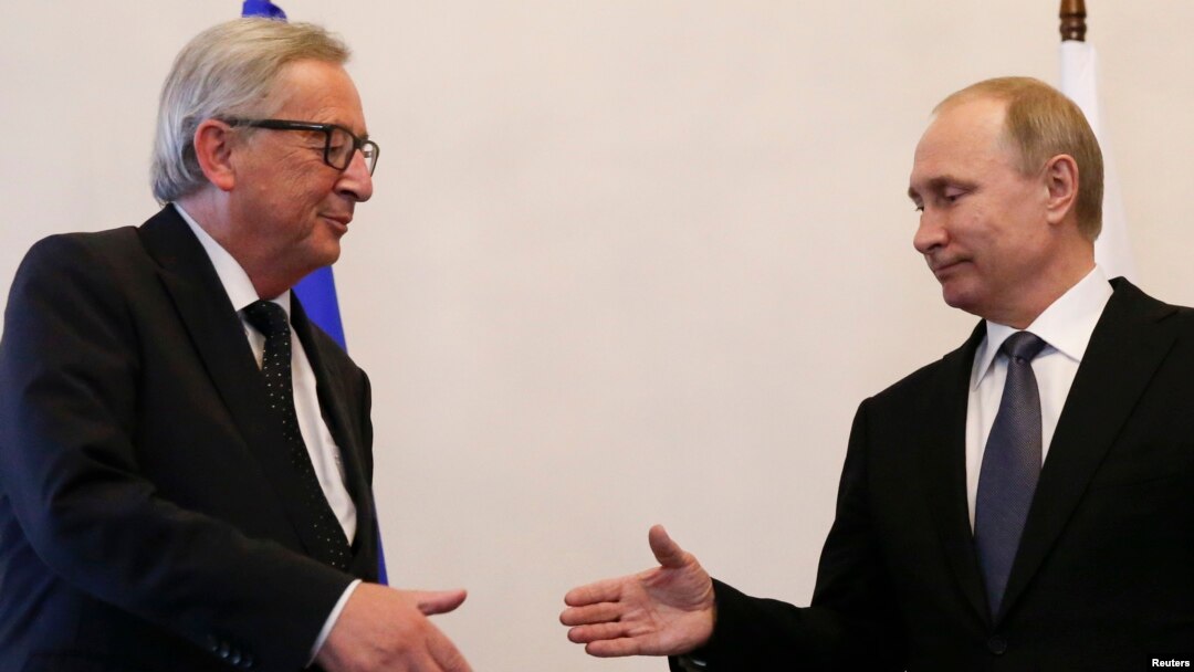 Russian President Vladimir Putin, right, approaches to shake hands with European Commission President Jean-Claude Juncker during a meeting in St. Petersburg, Russia, June 16, 2016. 