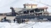 Afghan men stand in front of a collapsed building of a military base after a car bomb attack in Maidan Wardak, Afghanistan, Jan. 21, 2019. 