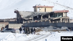 Afghan men stand in front of a collapsed building of a military base after a car bomb attack in Maidan Wardak, Afghanistan, Jan. 21, 2019. 