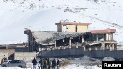 Afghan men stand in front of a collapsed building of a military base after a car bomb attack in Maidan Wardak, Afghanistan, Jan. 21, 2019. 