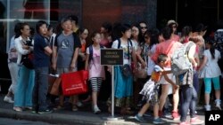 FILE - Chinese tourists line up to enter a fashion store in Paris Aug. 12, 2015. (AP Photo/Francois Mori)